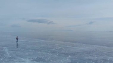 Baykal Gölü. Genç bir fotoğrafçı buzda yürüyor manzaranın tadını çıkarıyor ve fotoğraf çekiyor..