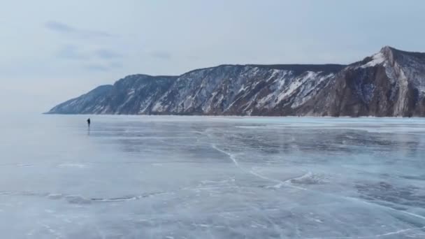 Озеро Байкал. Молодий фотограф ходить по льоду, насолоджуючись краєвидами і фотографує. — стокове відео