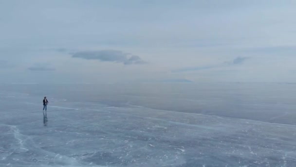 Озеро Байкал. Молодий фотограф ходить по льоду, насолоджуючись краєвидами і фотографує. — стокове відео