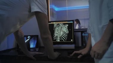 Kontrol Odası 'nda Doktor ve Radyolog, Prosedürü izlerken Arkaplan Hastası MR veya CT Tarama İşleminden Geçerken Tanıyı Tartışıyor.