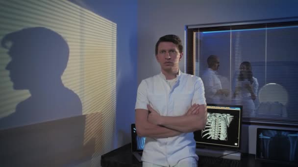 Gambar seorang dokter laki-laki. Dokter berdiri di ruang tomografi, dia tersenyum dan melihat ke kamera. Profesional orang di tempat kerja . — Stok Video