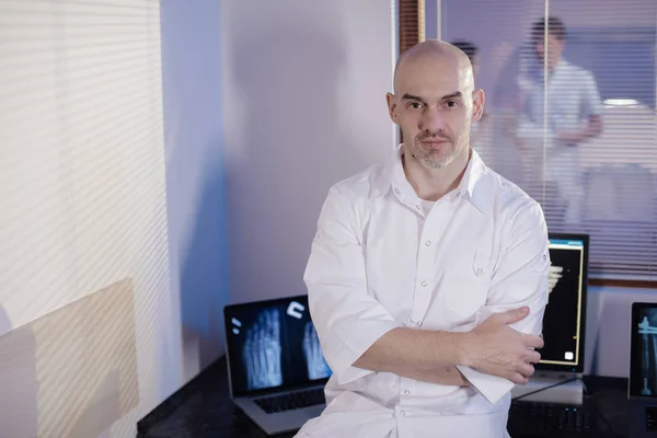 A picture of a male doctor. The doctor is standing in the tomography room, he smiles and looks at the camera. Professional people at work.