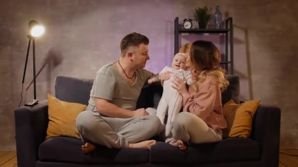 Young family sitting on the couch in a cozy room. Mom, dad and baby play together. Family happy — Stock Video
