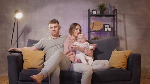 Young family sitting on the couch in a cozy room. Mom, dad and baby play together. Family happy — Stock Video