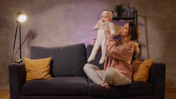 Genç bir aile rahat bir odada kanepede oturuyor. Anne, baba ve bebek birlikte oynuyorlar. Aile mutlu — Stok video