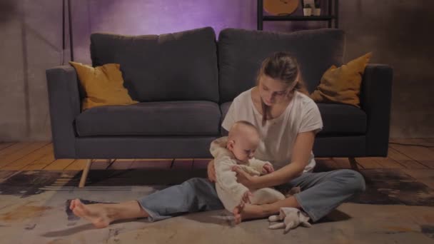 Женщина играет со своим ребенком на полу рядом с диваном в уютной квартире. Мама и ребенок счастливы. — стоковое видео