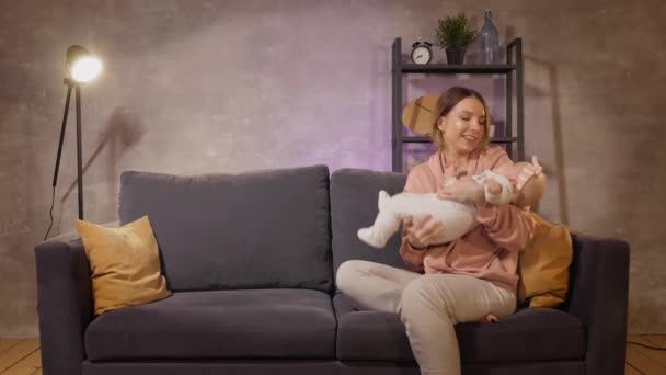 A young family sits on the couch and play together. Mom, dad and daughter are happy. The man made a gift to his wife. — Stock Video