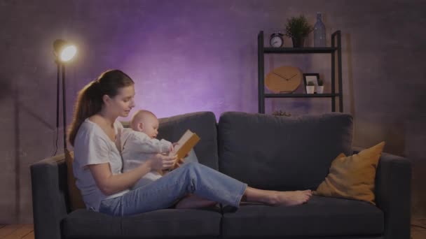 Eine Frau spielt mit ihrem Kind auf dem Sofa in einer gemütlichen Wohnung. Mutter und Baby sind glücklich — Stockvideo