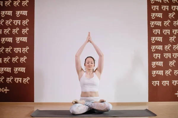 Joven mujer atractiva deportista practicando yoga, meditando en pose de yoga, haciendo ejercicio, usando ropa deportiva, estudio de yoga ligero — Foto de Stock