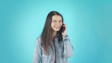A young Smiling Woman in a Denim Jacket is Talking on the Phone and Laughing