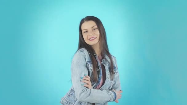 Lächelnde brünette Frau in Jeansjacke zeigt ok Zeichen und schaut in die Kamera über türkisfarbenem Hintergrund — Stockvideo