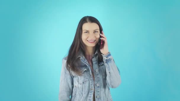 Молодая улыбающаяся женщина в джинсовой куртке разговаривает по телефону и смеется — стоковое видео