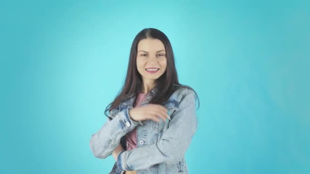 Улыбающаяся брюнетка в джинсовой куртке взрывает поцелуй в камеру — стоковое видео