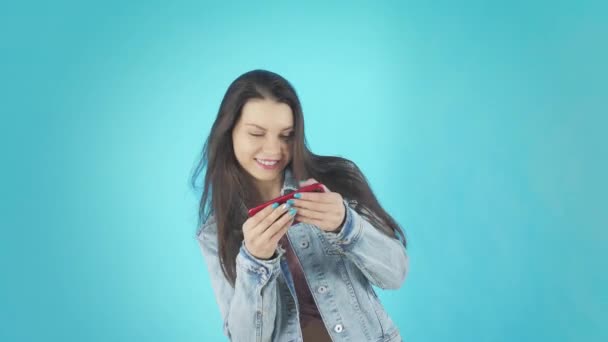 Una giovane donna sorridente in giacca di denim gioca al telefono — Video Stock