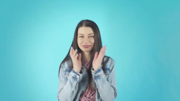 Young worried girl standing with fingers crossed for good luck and wins isolated over blue background — Stockvideo