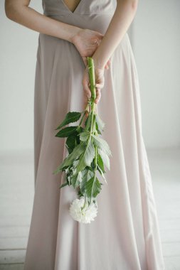 Pembe elbiseli, elinde bir buket çiçekle Gri Arkaplan 'da çiçek buketi tutan güzel kız.