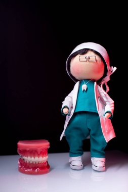 Full-length dentist doll. Next to the dentist put the jaw with braces. Demonstration of teeth. Vertical video