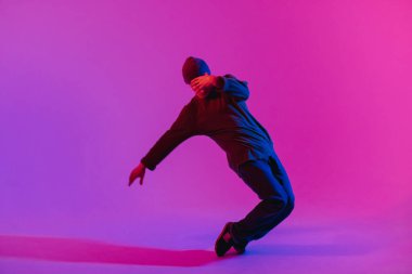 Jumperlı Genç Adam Stüdyoda Çağdaş Dans Ediyor. Breakdance. Dans okulu posteri. Uzayı kopyala Savaş yarışması duyurusu. Pembe ve Mavi Arkaplan.