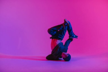 Jumperlı Genç Adam Stüdyoda Çağdaş Dans Ediyor. Breakdance. Dans okulu posteri. Uzayı kopyala Savaş yarışması duyurusu. Pembe ve Mavi Arkaplan.