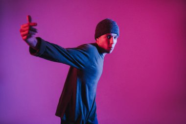 Jumperlı Genç Adam Stüdyoda Çağdaş Dans Ediyor. Breakdance. Dans okulu posteri. Uzayı kopyala Savaş yarışması duyurusu. Pembe ve Mavi Arkaplan.