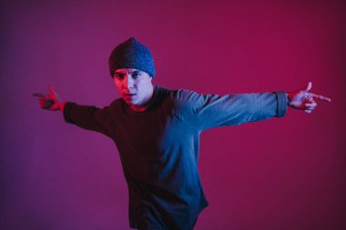 Jumperlı Genç Adam Stüdyoda Çağdaş Dans Ediyor. Breakdance. Dans okulu posteri. Uzayı kopyala Savaş yarışması duyurusu. Pembe ve Mavi Arkaplan.