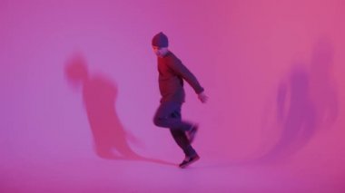 Jumperlı Genç Adam Stüdyoda Çağdaş Dans Ediyor. Breakdance. Dans okulu posteri. Uzayı kopyala Savaş yarışması duyurusu. Pembe ve Mavi Arkaplan.