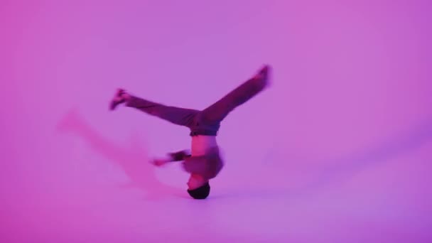 Молодой человек в джампере танцует современный танец в студии. Брейкданс Плакат танцевальной школы. Скопируй пространство. Объявление соревнований. Розовый и синий фон. — стоковое видео