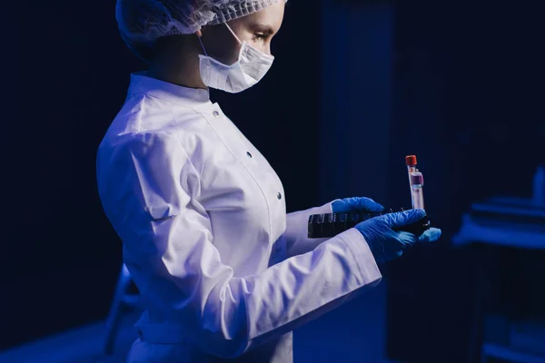 젊은 여성 의사가 의료용 마스크를 쓰는 모습. 의사 가손에 핵무기를 쥐고 있다 — 스톡 사진