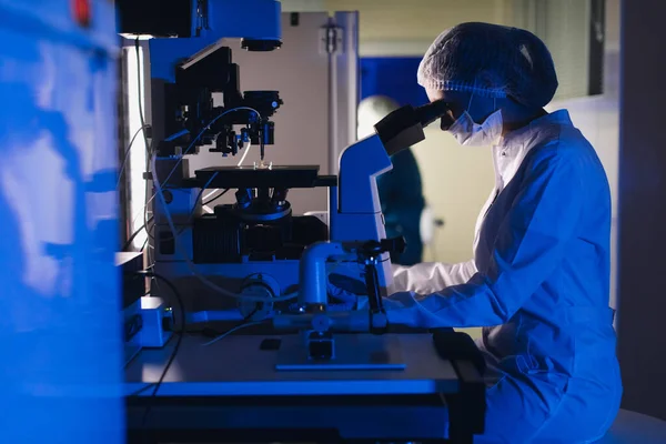 In a Modern Laboratory Scientist Conduct Experiments. El embriólogo examina muestras con un microscopio — Foto de Stock