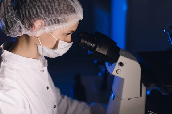 In a Modern Laboratory Scientist Conduct Experiments. Científico jefe de investigación ajusta el espécimen en un plato de Petri y lo mira en el microscopio . — Foto de Stock