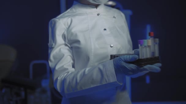 Portrait of Young Female Doctor in Medical Mask Looking at Camera. The doctor Holds the Cones in his Hands — Stock Video