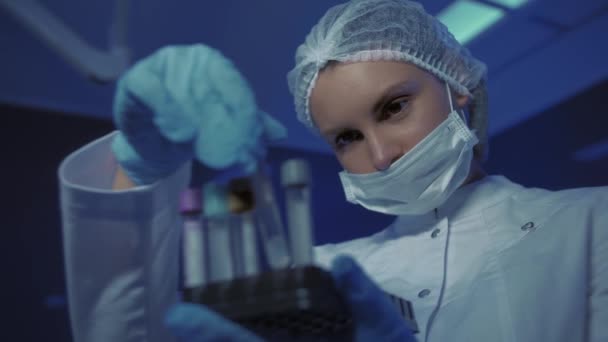 Portrait of Young Female Doctor in Medical Mask Looking at Camera. The doctor Holds the Cones in his Hands — Stock Video