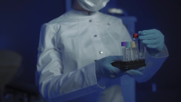 Portrait of Young Female Doctor in Medical Mask Looking at Camera. The doctor Holds the Cones in his Hands — Stock Video