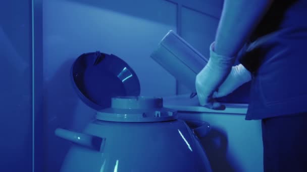 Специалист-эмбриолог забирает капсулу с эмбрионами из криобанка — стоковое видео