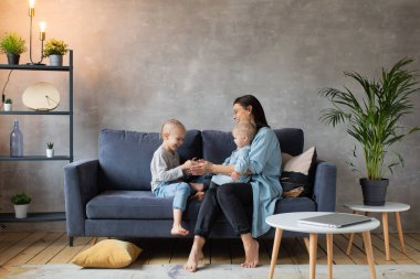 Genç Anne Kanepede Çocuklarla Oynuyor. Mutlu bir aile. ev konforu.