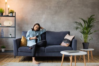 Genç bir kız koltukta oturuyor ve mesajlaşıyor..