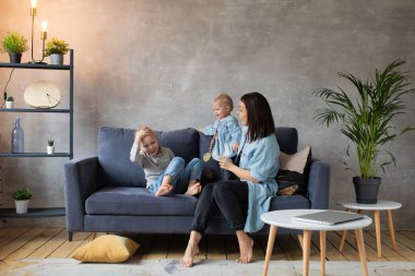 Genç Anne Kanepede Çocuklarla Oynuyor. Mutlu bir aile. ev konforu.