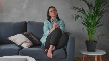Genç bir kadın koltukta oturuyor ve kameraya bakıyor. Kız endişeli, Hüzünlü. Depresyon.