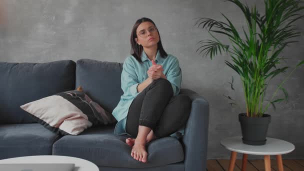 En ung kvinna sitter i soffan och tittar på kameran. Flickan är orolig, Sad. Depression. — Stockvideo