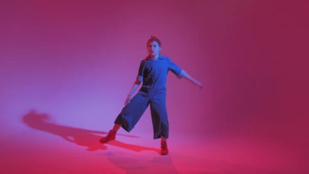 Joven chica elegante bailando en el estudio sobre un fondo de neón de color. Diseño de póster de música dj . — Vídeo de stock