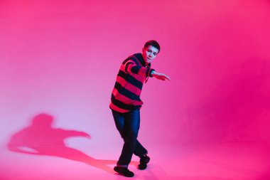 Jumperlı Genç Adam Stüdyoda Çağdaş Dans Ediyor. Breakdance. Dans okulu posteri. Uzayı kopyala Savaş yarışması duyurusu. Pembe ve Mavi Arkaplan.