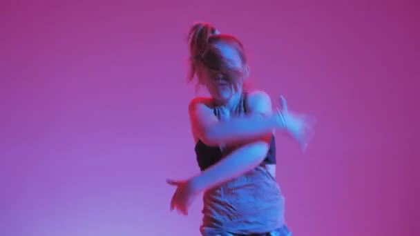 Mladá stylová dívka tančí v ateliéru na barevném neonovém pozadí. Design plakátu Music DJ. — Stock video