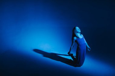 Stüdyoda renkli neon bir arka planda dans eden zarif genç bir kız. Klasik dansçı..