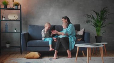 Genç Anne Kanepede Çocuklarla Oynuyor. Mutlu bir aile. ev konforu.