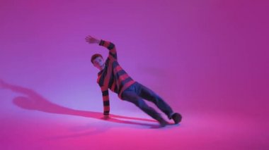 Jumperlı Genç Adam Stüdyoda Çağdaş Dans Ediyor. Breakdance. Dans okulu posteri. Uzayı kopyala Savaş yarışması duyurusu. Pembe ve Mavi Arkaplan.