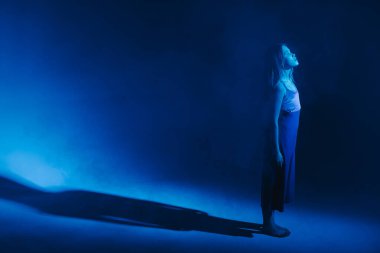 Stüdyoda renkli neon bir arka planda dans eden zarif genç bir kız. Klasik dansçı..