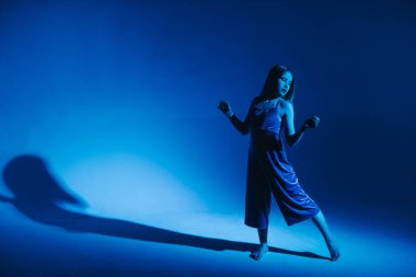 Stüdyoda renkli neon bir arka planda dans eden zarif genç bir kız. Klasik dansçı..