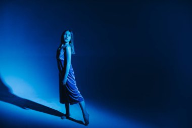 Stüdyoda renkli neon bir arka planda dans eden zarif genç bir kız. Klasik dansçı..