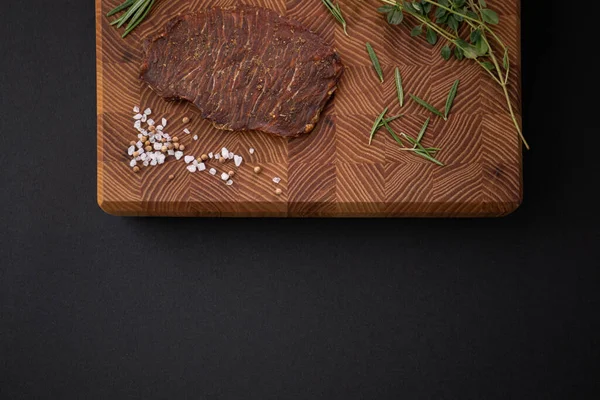 Close-up de um pedaço de carne em uma tábua de madeira com especiarias. Menu restaurante, uma série de fotos de diferentes pratos — Fotografia de Stock