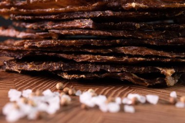 Ahşap bir tahtanın üzerinde, baharatlı bir et parçasının yakın çekimi. Restoran menüsü, bir dizi farklı yemeğin fotoğrafları.